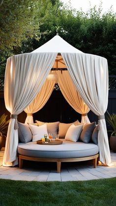 an outdoor day bed with curtains and pillows on the top is lit up at night