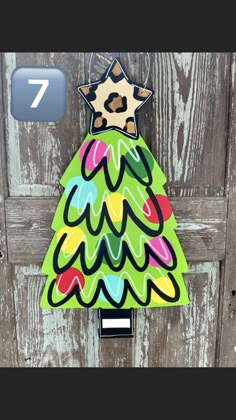 a christmas tree shaped door hanger on a wooden door with the number seven painted on it