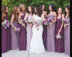 a group of women standing next to each other wearing purple dresses and holding bouquets