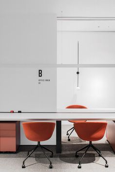 two orange chairs sitting at a table in an office with white walls and flooring