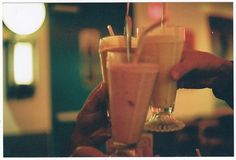 two people holding drinks in their hands with straws on the top and one is empty