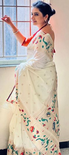 a woman in a white sari poses for the camera with her hand on her hip