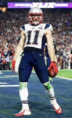 a football player is standing on the field with his hands in his pockets and holding a ball