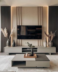 a living room with a large television and two vases on the table in front of it