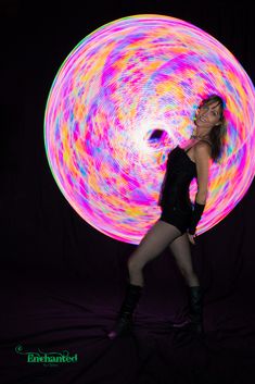 a woman is posing in front of a colorful light ball with her hands on her hips