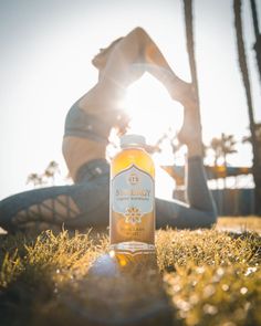 a woman sitting in the grass next to a bottle of sun energy