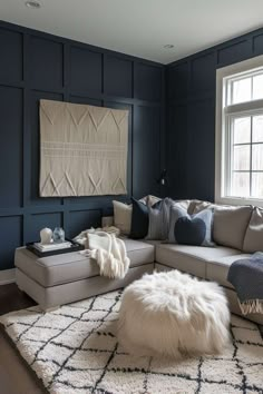 a living room with blue walls and white rugs on the floor in front of a large sectional couch