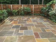 an outdoor patio with stone pavers and wood fence