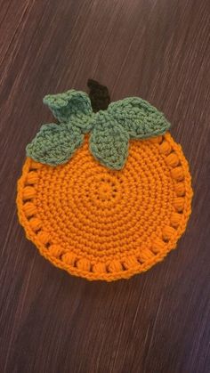 an orange crocheted placemat sitting on top of a wooden table