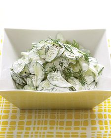 a white bowl filled with cucumber salad on top of a yellow and white table cloth