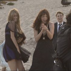 three women and two men laughing on the beach