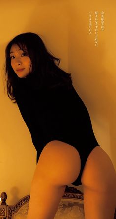 a woman in a black bodysuit leaning against a wall