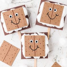 four pieces of brown paper with faces on them and sticks sticking out of the middle