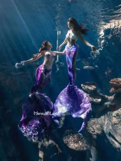 two mermaids are swimming in the water