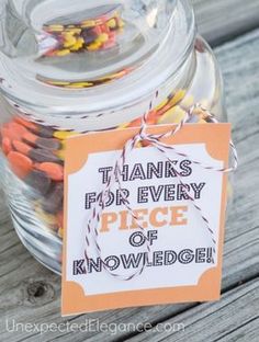 a jar filled with candy sitting on top of a wooden table next to a sign that says thanks for every piece of knowledge