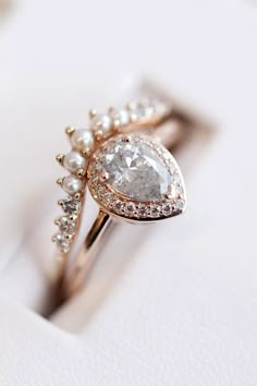 an engagement ring with a pear shaped diamond surrounded by small white pearls and gold plating