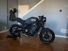 a black motorcycle parked in front of a stair case on a hard wood floor next to a door