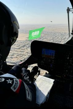 two pilots in the cockpit of an airplane flying over land and water with green flags