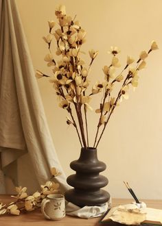 a vase filled with flowers sitting on top of a wooden table next to a book