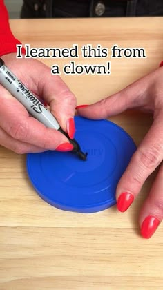 a woman with red nails is using a marker to draw on a blue object that reads, i learned this from a clown