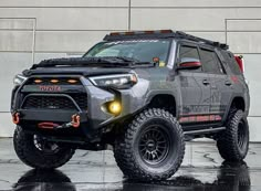 the front end of a gray toyota 4runner with its lights on and black tires