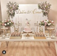 a table topped with a cake surrounded by candles and vases filled with pink flowers