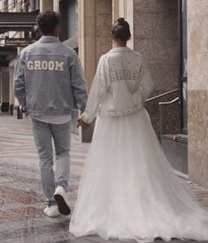 a bride and groom walking down the street holding hands