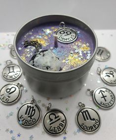 the zodiac sign charms are on display in a metal container with confetti sprinkles around them