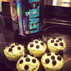 four cupcakes sitting on top of a counter next to a bottle of energy drink