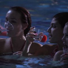 three women are in the water drinking from wine glasses