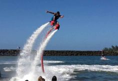 a man is doing tricks on water skis while people watch from the shore line