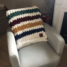 a white chair with a multicolored knitted pillow sitting on top of it