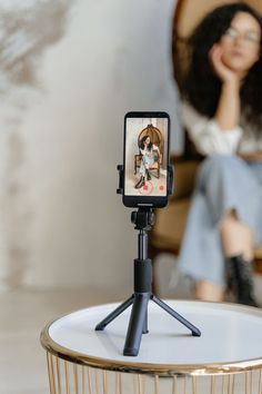 a cell phone sitting on top of a tripod next to a doll in the background