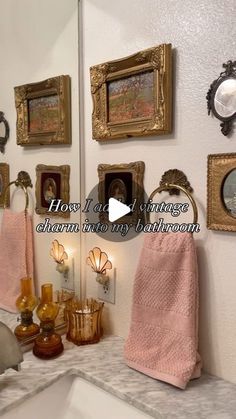 there is a bathroom with pictures on the wall and towels hanging up in front of the sink