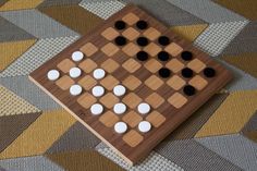 a wooden chess board with white and black pieces on it sitting on a carpeted floor