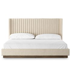 an upholstered bed with white sheets and pillows on the headboard is shown