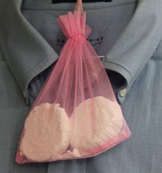 a pink organ bag with two powdered white hearts in it, hanging from the back of a man's shirt