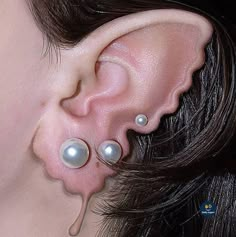 a close up of a person's ear with two pearls attached to the side