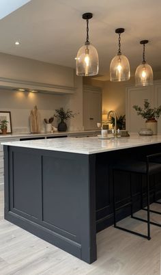 a large kitchen island with three hanging lights above it