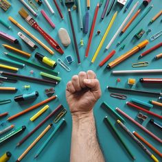 a man's fist surrounded by many different colored pencils