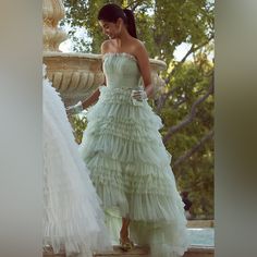 a woman in a green dress standing next to a fountain