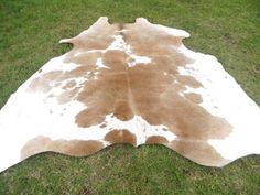 a brown and white cow skin rug on grass