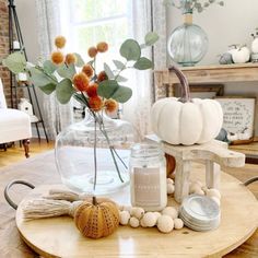 a wooden table topped with a vase filled with flowers and other items next to a window