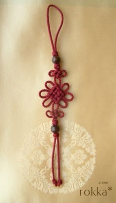 a red string is attached to a white doily with an intricate design on it