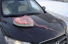 a black car with a heart shaped object on the hood and chain attached to it