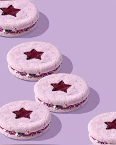 four cookies with purple icing and stars on them