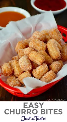 some sugared donuts in a red basket next to dipping sauces on a table