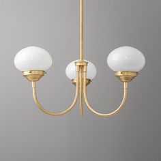 three light chandelier with white glass balls hanging from it's brass finish