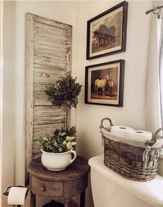 a bathroom with two pictures on the wall and a potted plant next to it