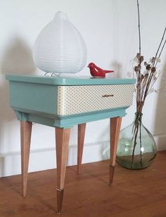 a small table with a bird on it next to a vase